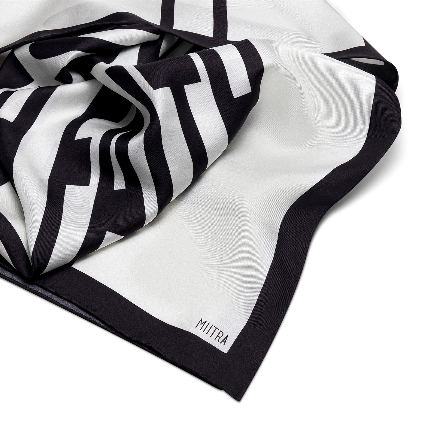 Liberation Silk Scarf - detail shot of ivory and black silk scarf with close up of branding